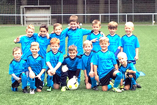 Kinder im Fußballverein tragen hell-blaue Trikots und Fußballtrikots. Fröhliche Jungen üben Fußball